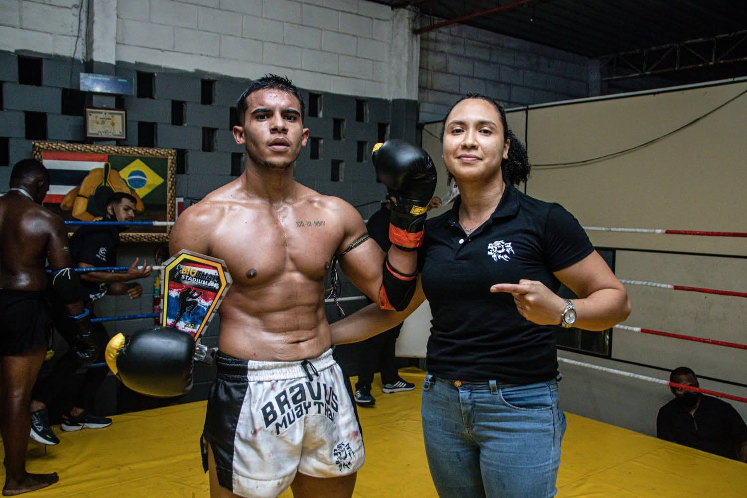 Atleta Bravus com cinturão de Muay Thai ao lado da professora Camila